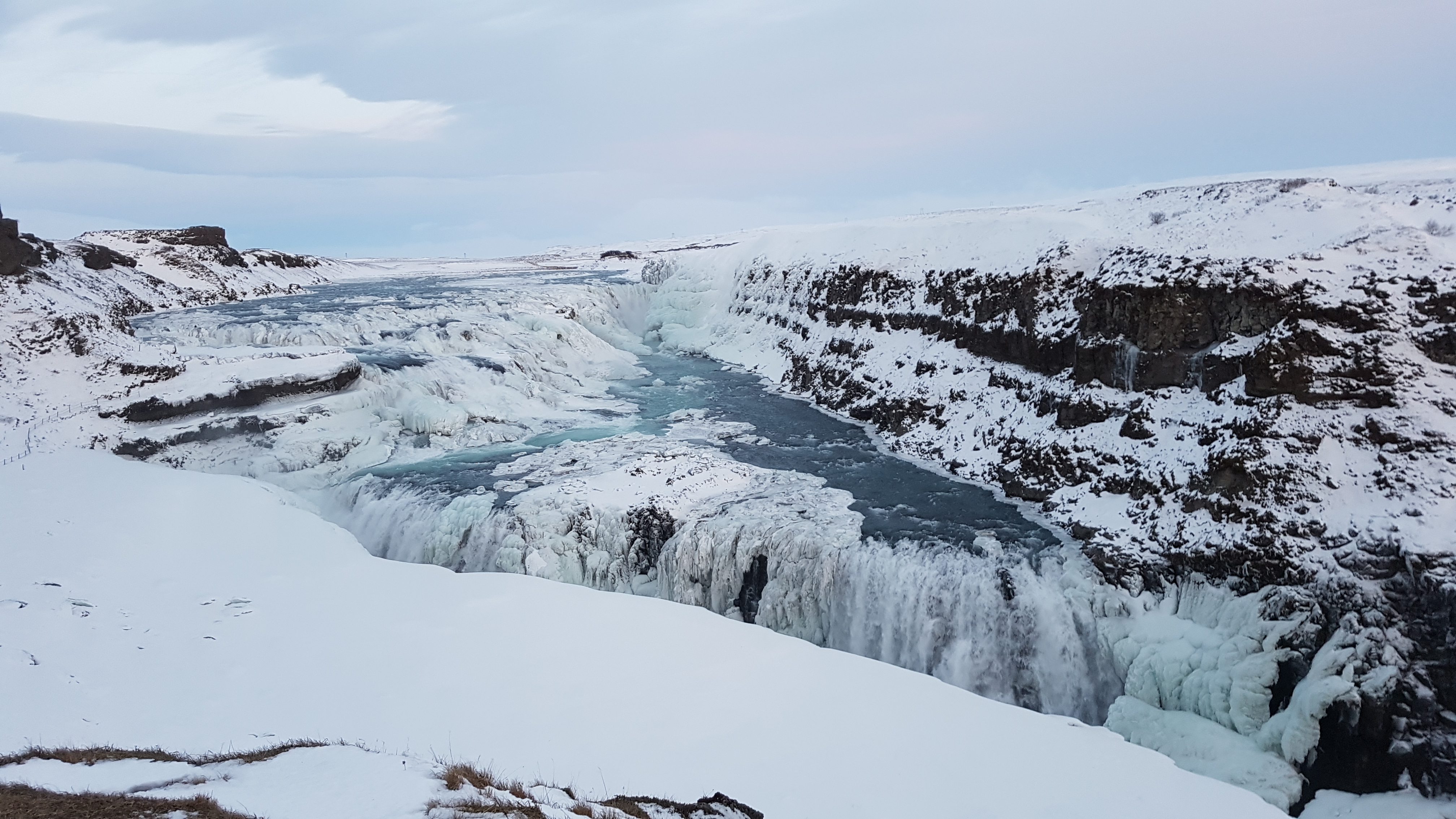 Panoramic view of Gullfoss waterfall cascading into its canyon with mist rising