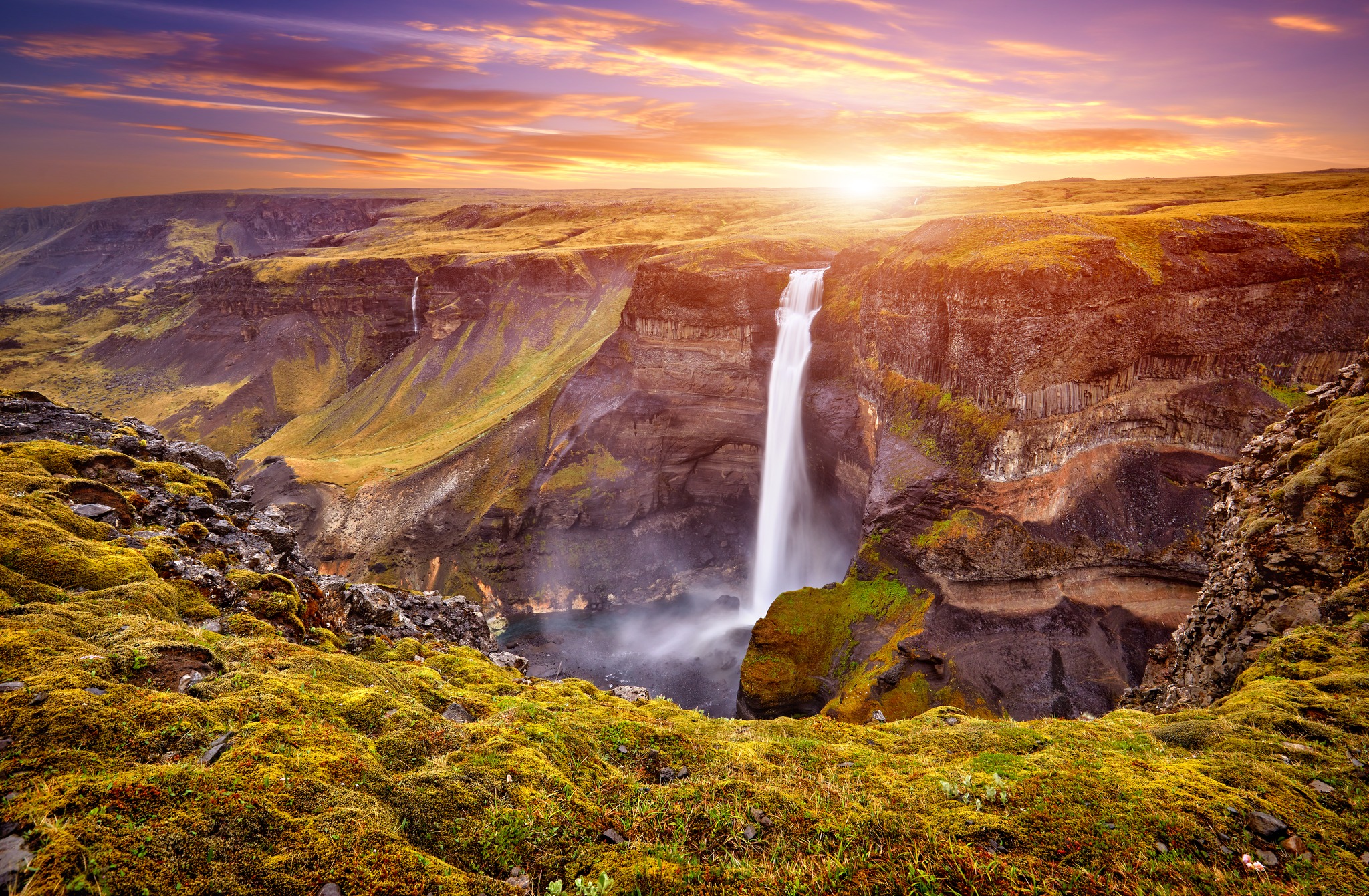 Háifoss waterfall plunging 122 meters into a canyon at sunset with golden light over the Icelandic highlands
