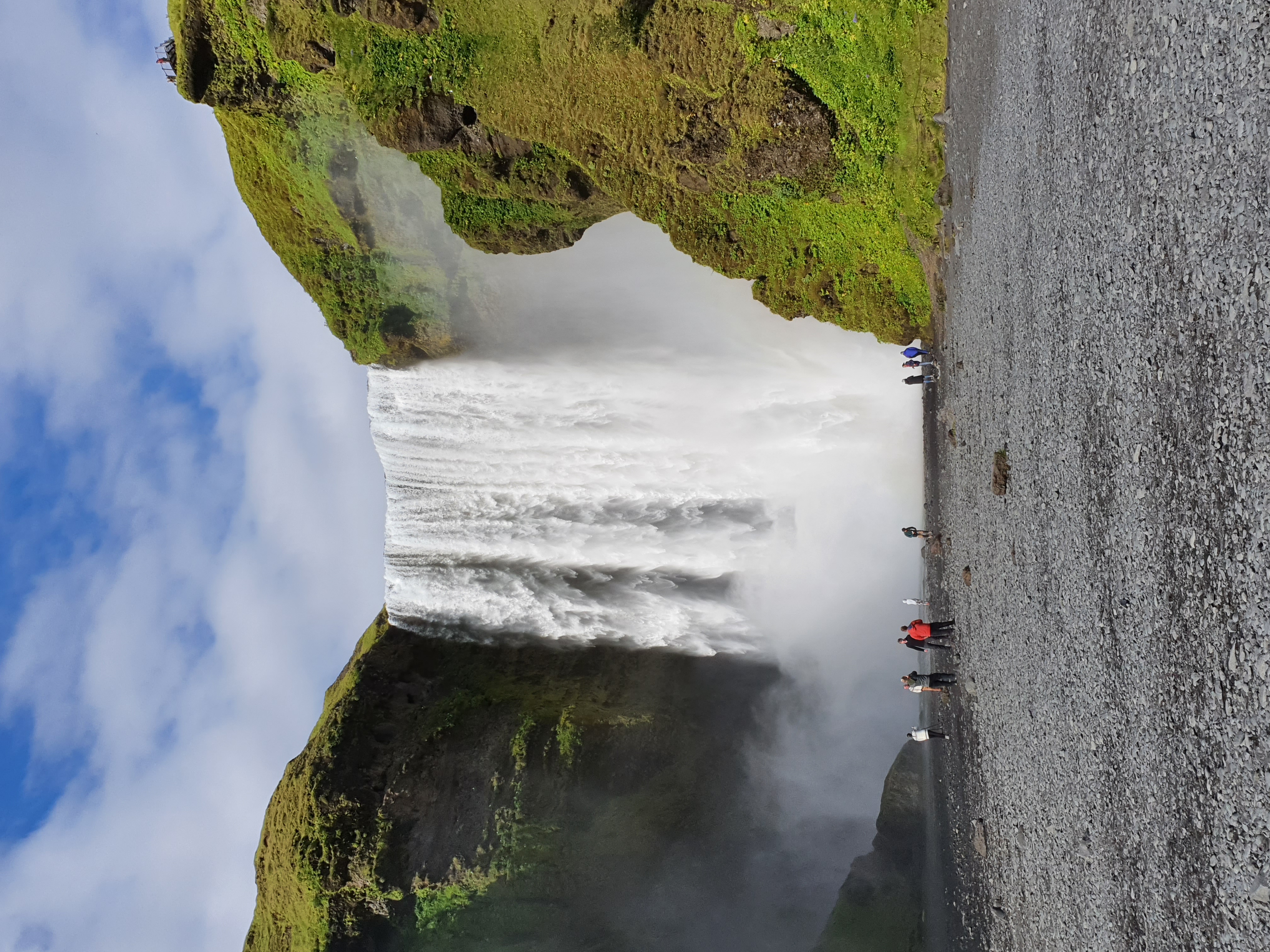 Skógafoss waterfall with visitors at its base showing the immense scale