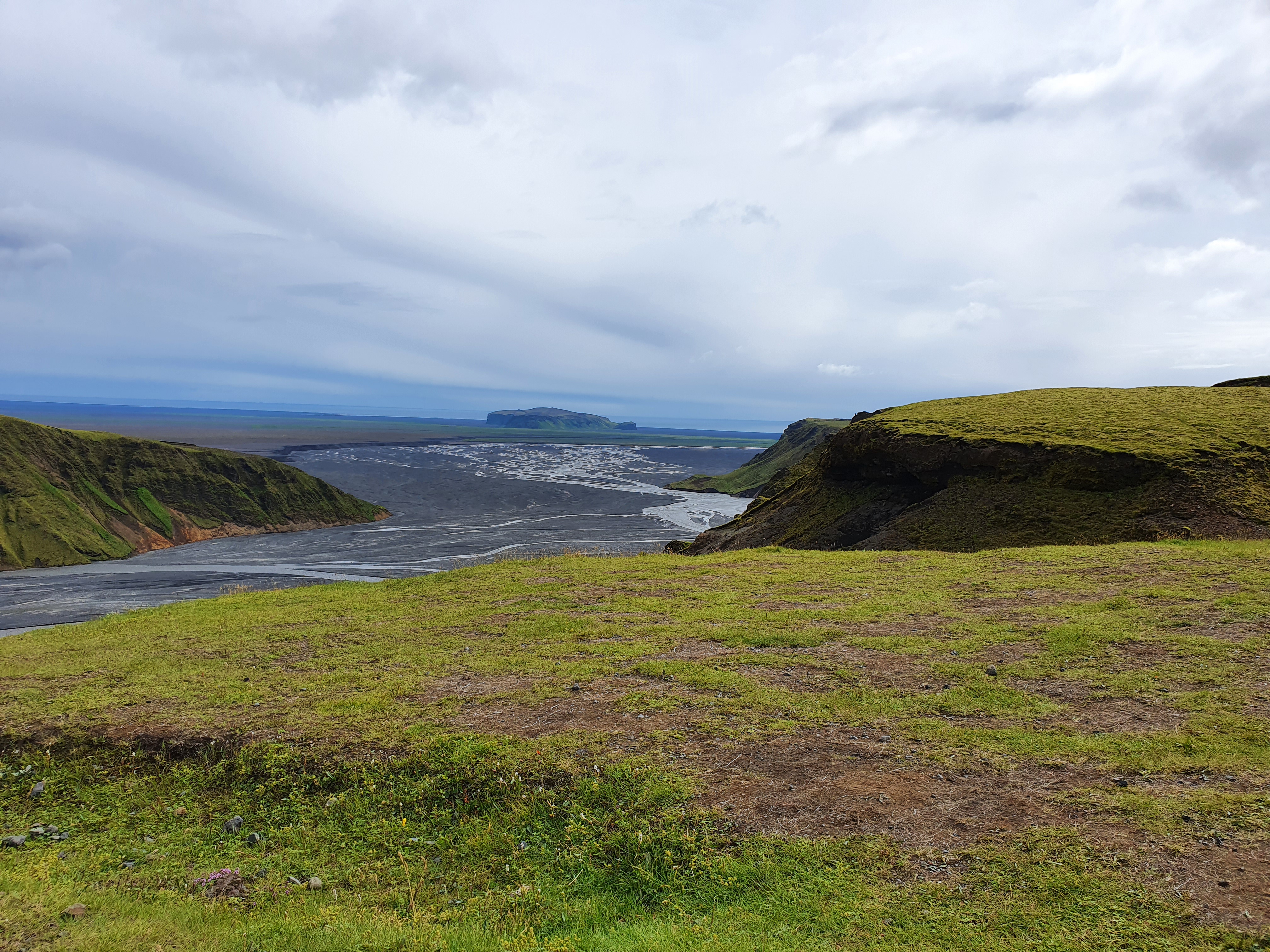 Skógafoss waterfall from a distance showing the cliff and surrounding landscape