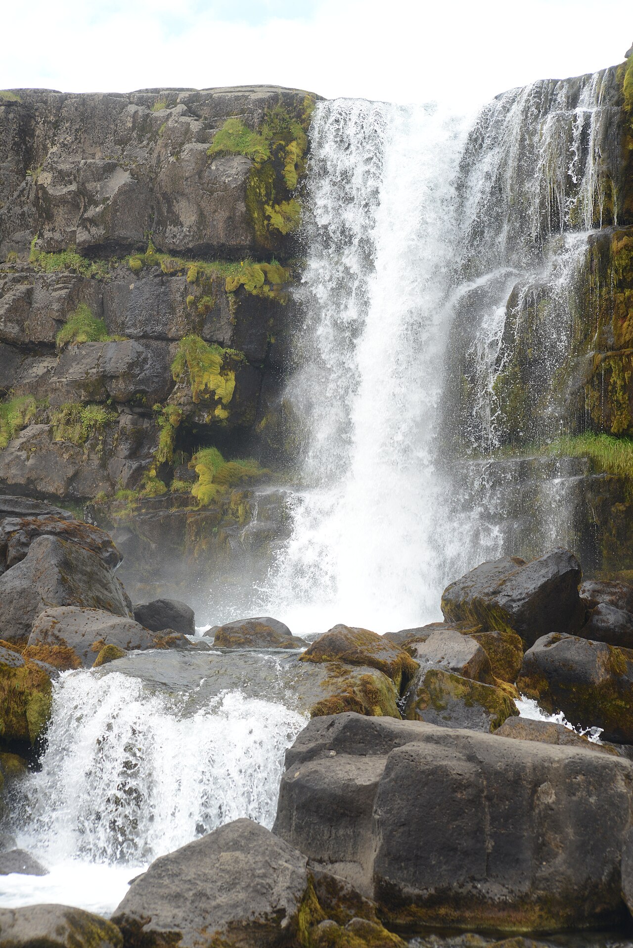 Öxarárfoss waterfall cascading over mossy rocks in summer